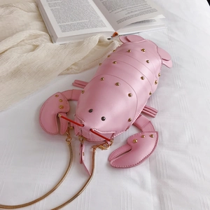 Detail of pink lobster shaped bag with gold studs and chain strap on white bedding