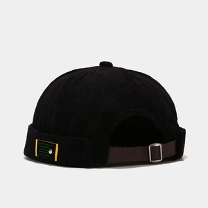 Detail of black corduroy docker hat featuring adjustable brown leather back strap