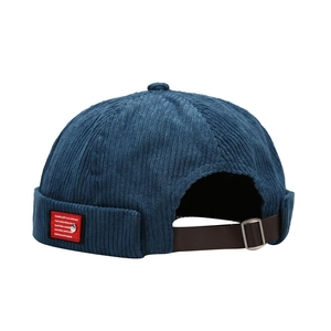 Blue corduroy docker hat with leather strap and metal buckle on white background