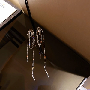 Silver geometric tassel earrings with glittering diamonds shown on a reflective surface