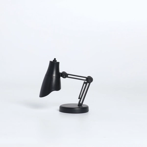 Gros plan d'une mini lampe de bureau LED noire à articulations sur fond blanc