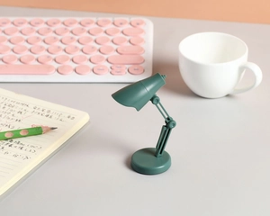 Gros plan d'une mini lampe de lecture LED verte réglable sur un bureau avec un clavier