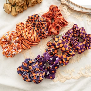 Eight Halloween velvet scrunchies with orange and purple patterns on vintage lace background