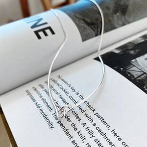 Detail of silver knot chain necklace laid over an artistic fashion magazine background