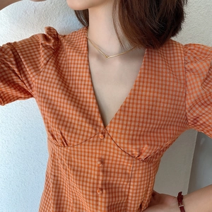 Detail of V-neck orange plaid dress with puff sleeves and button accents on cotton fabric