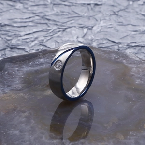 Detailed close-up of polished silver steel ring with blue diagonal groove and small diamond