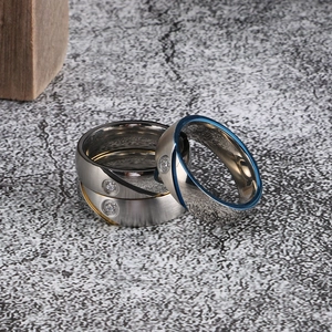 Close-up of three-piece set of stainless steel rings with zircon inlay in gold, silver and blue
