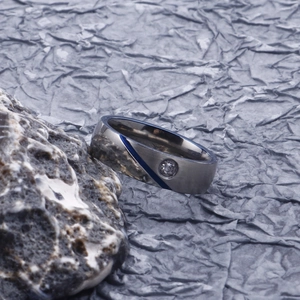 Detailed macro view of silver stainless steel ring with blue stripe and small gem on stone