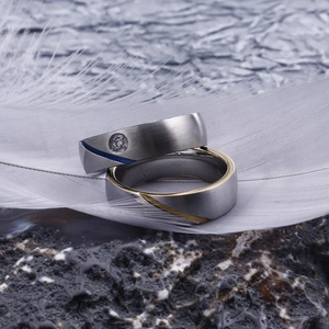 Macro shot of brushed stainless steel couple rings with zircon inlay and color stripes