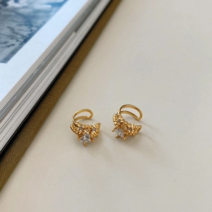 Close-up of gold star ear cuffs with sparkling zircon crystals on a minimalist background
