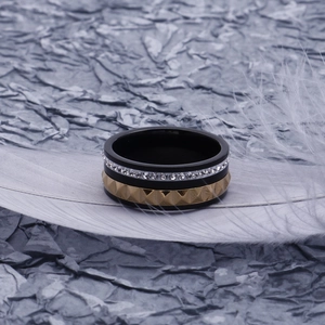 Vue détaillée d'une bague de mode noire et dorée avec strass blancs sur des plumes douces