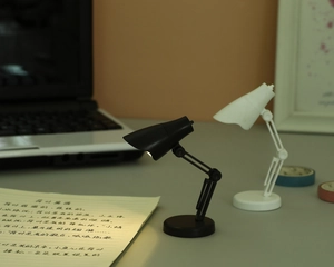 Mini lampe de lecture LED avec bras réglable et lumière chaude sur un bureau