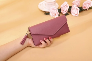 Detailed view of a purple litchi grain leather wallet with a heart pendant and tassel