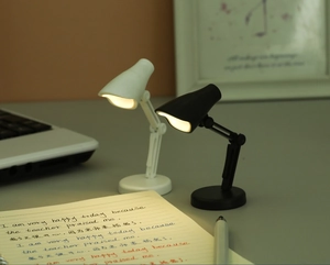 Mini lampes de bureau LED noires et blanches avec bras flexibles sur un bureau d'étude