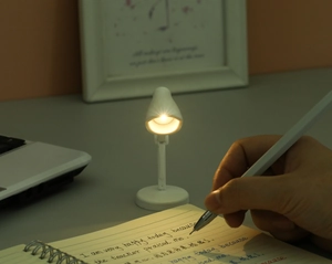 Mini lampe de lecture LED à col flexible éclairant un carnet dans une pièce sombre