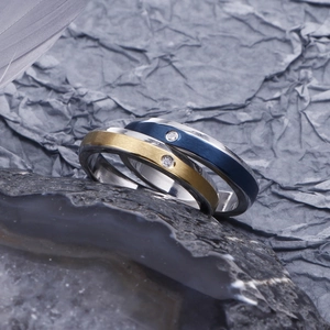 Detail of brushed metal couple rings with small diamond inlay on dark stone