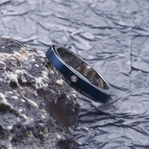 Detail of blue brushed metal ring with black inner band and small diamond accent