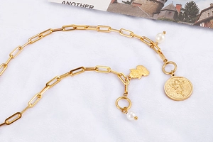 Detail of gold titanium chain necklace featuring a pearl and engraved angel pendant charm