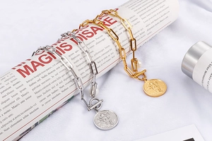 Detail of gold and silver chunky chain necklaces with pearls and angel coin pendants