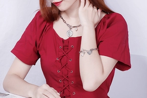 Close-up of pearl and coin pendant necklace and heart charm bracelet on model