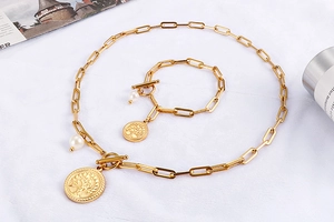 Détail d'un ensemble de chaînes dorées avec pendentifs Arbre de Vie et perles sur texture