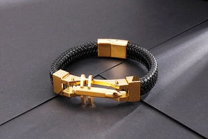 Detail of men's titanium steel leather bracelet with gold bullet charm and magnetic clasp