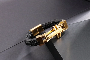 Detailed view of black braided leather bracelet with golden bullet-shaped magnetic clasp
