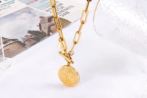Détail du collier chaîne trombone dorée avec perle, fermoir à bascule et pendentif religieux