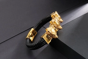 Dettaglio del bracciale in pelle intrecciata nera con tre teste di lupo dorate su gradini