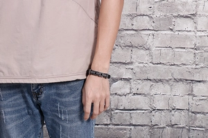 Close-up of men's braided titanium steel and black leather拼接 bracelet worn on wrist