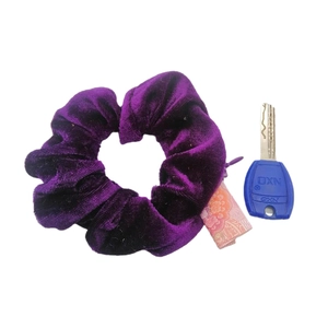 Deep purple velvet scrunchie with zipper pocket shown next to key for size reference