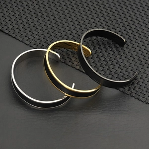 Three minimalist C-shaped open bangles in silver, gold, and black on a leather background