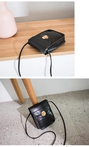 Detail of black crocodile texture phone bag with elegant gold twist lock and slim strap