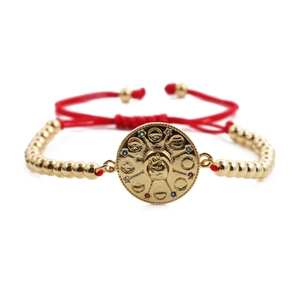 Goldenes Perlenarmband mit roter Kordel und rundem Zirkonia-Anhänger auf weißem Grund