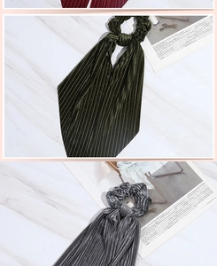 Detail of dark green and grey corduroy scrunchies with long ribbons on marble