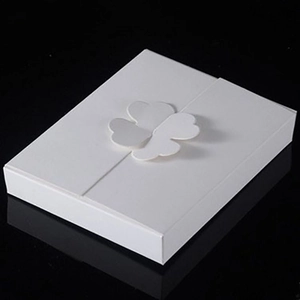 Elegant white four-leaf clover cardboard gift box on black reflective surface
