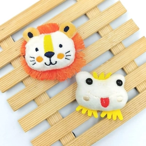 Close-up of plush lion and frog pins featuring detailed fringe and embroidery