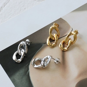 Detailed view of 18K gold and silver chunky link chain earrings on a fashion magazine