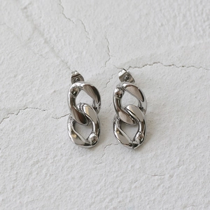 Detailed view of silver chain link earrings with polished finish on textured background