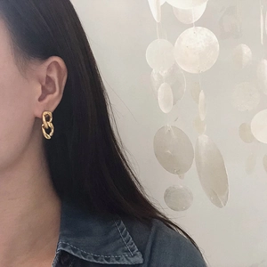 Close-up of chunky gold-plated chain earrings worn by model for a minimalist style