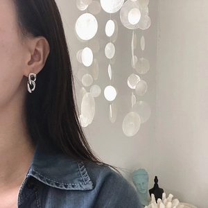 Detail view of bold geometric chain link earrings in silver finish worn by a model