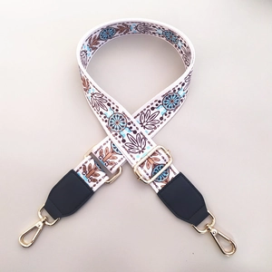 Detail of adjustable floral fabric strap with gold metal hooks and bohemian pattern