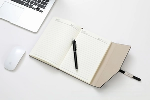 Close-up of business notebook with lined paper, premium metal pen, and leather cover