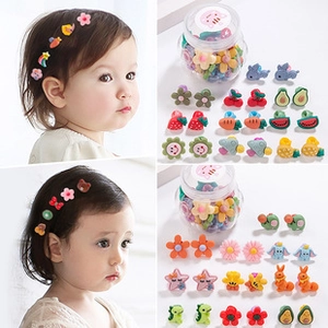 Close-up of colorful variety kids hair clips including fruit and animals with storage jar