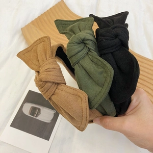 Detailed view of three velvet bow headbands in brown, green, and black fabric