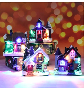 Close-up of four glowing resin Christmas house ornaments with warm LED lights and bokeh
