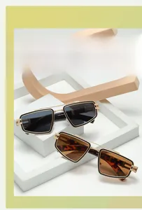 Detail of geometric sunglasses with gold frames and printed model specs on the temple