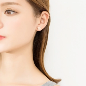 Elegant white daisy stud earrings with gold center worn by a model in a close-up shot