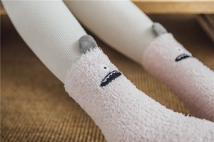 Close-up of pink coral fleece socks featuring 3D monster ears and cute embroidered details
