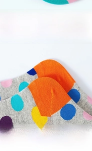 Detailed view of the reinforced orange heel and flat seam toe on gray polka dot socks
